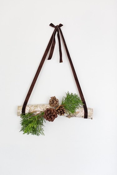 hanging log decor with pine cones and grass