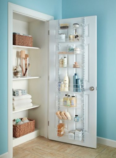 Closet organizer with linens, door rack with cleaning supplies.