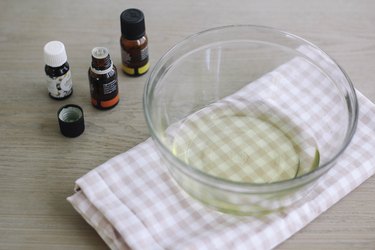Essential oils next to bowl of melted soy wax