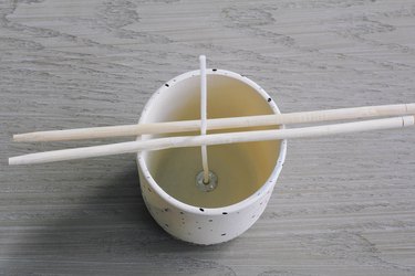 Chopsticks holding wick in homemade candle making DIY