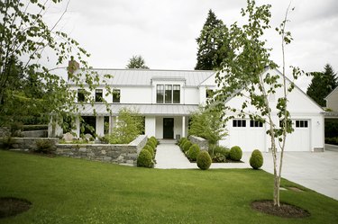 modern white farmhouse with boxwood shrubs