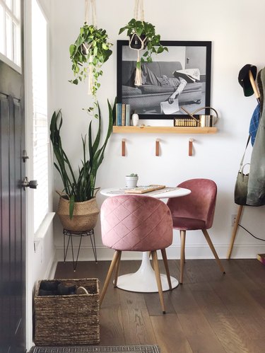 Woven entryway shoe storage with basket in entryway next to table and pink chairs