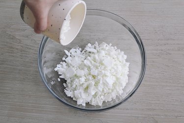 Pouring soy wax flakes into glass bowl