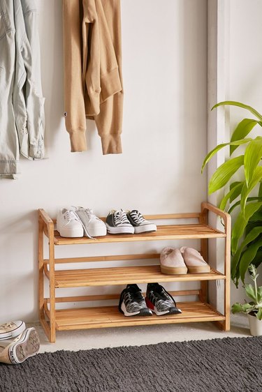 Bamboo rack for entryway shoe storage with a few pairs of shoes in entryway