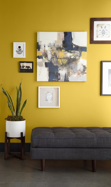 yellow wall with framed art and dark gray couch