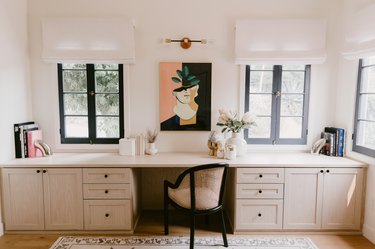 neutral toned modern home office with long built-in desk beneath a set of windows