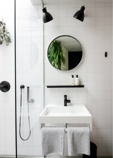 small minimalist bathroom with round vanity mirror and black fixtures