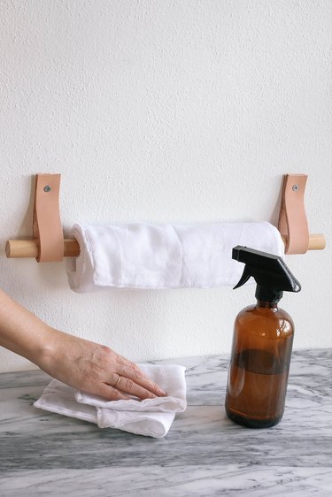 DIY reusable fabric paper towels hanging on wood and leather paper towel holder