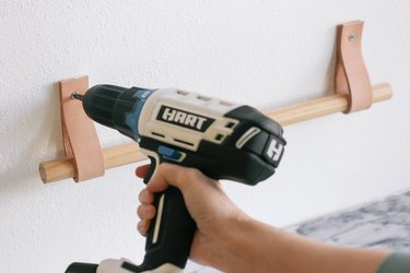 Drilling screws to attach leather straps to wall