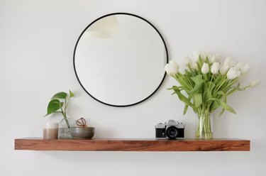 IKEA Lack shelf with walnut cover, mirror, and flowers