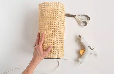 Wrapping cane around a vase with glue gun and scissors