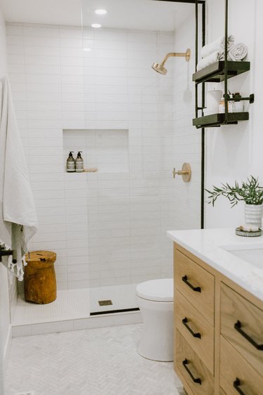 black bathroom shelving above toilet next to wooden vanity cabinet