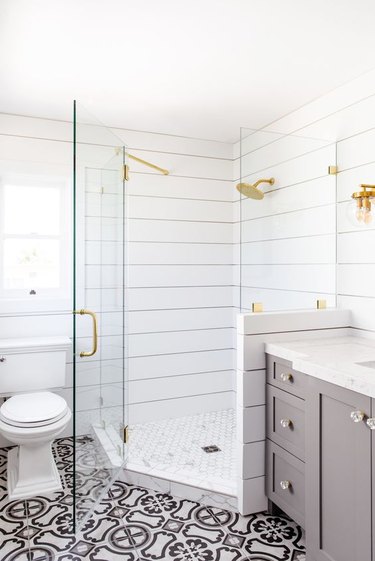 Corner shower with white shiplap walls and brass fixtures