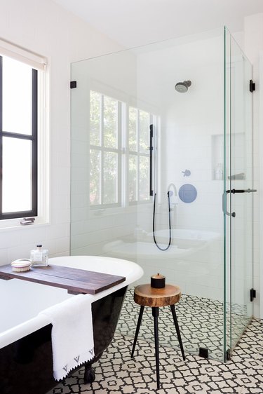black and white bathroom with freestanding glass shower door and tub