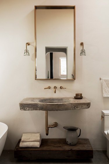 brass framed mirror and rustic bathroom shelving