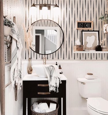 small modern bathroom with black and white wallpaper  and round mirror
