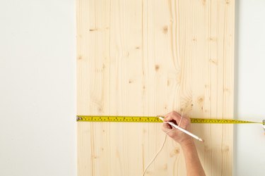 Hand with measuring tape on wood board