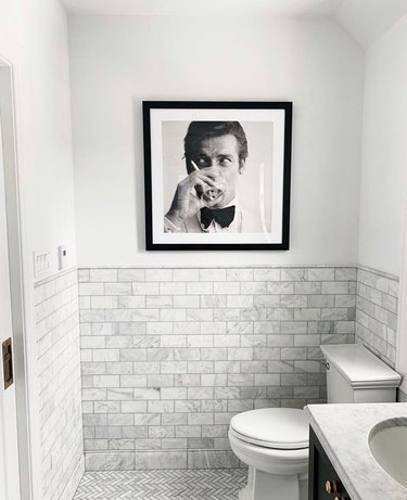 small modern bathroom with marble subway tile and black and white photograph