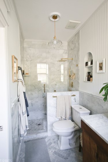 Marble tile in a shower with brass accents in farmhouse bathroom