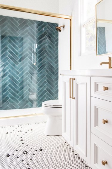 white bathroom with teal shower tile wall and brass hardward plus mosaic tile floor