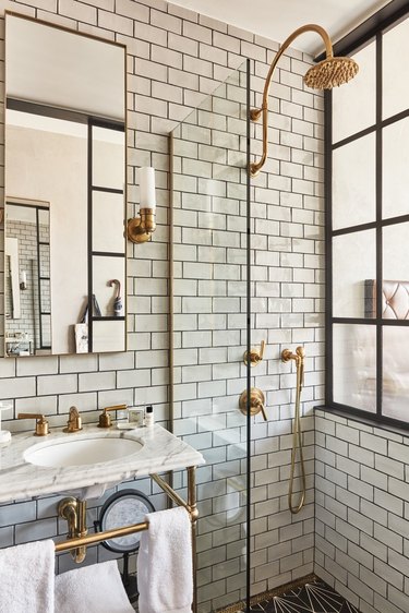 Industrial bathroom with white subway tile and brass shower fixtures