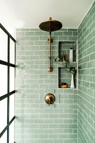 Green tile shower in light green subway tile with brass fixtures