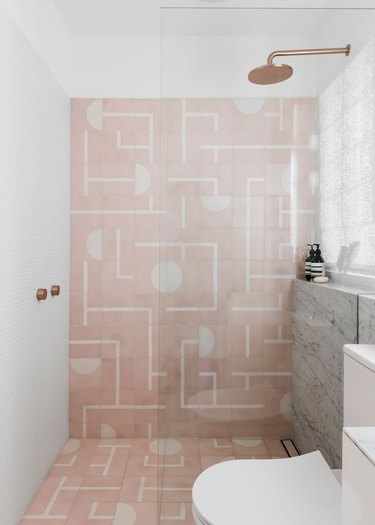 white bathroom with pink patterned tiles in the shower