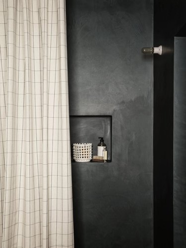 Black concrete shower with black and white gridded shower curtain