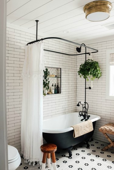 Industrial bathroom with white subway tile and black and white clawfoot bathtub