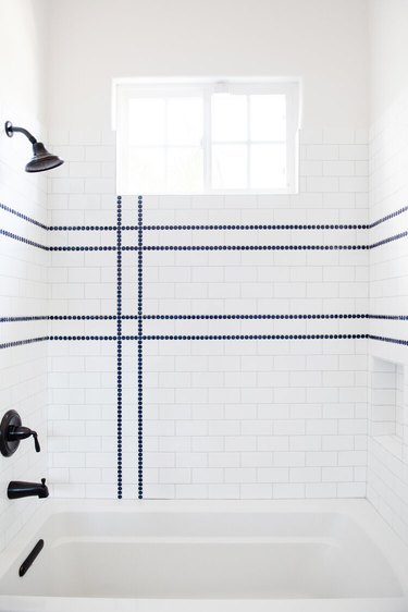 Coastal shower with white subway tile and blue tile stripes