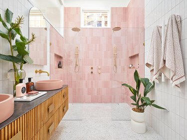 white bathroom with pink tiles in the shower and wooden vanity