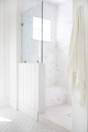 Coastal shower with glass, shiplap, and a white marble wall