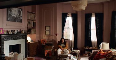 person in millennial pink room with black curtains