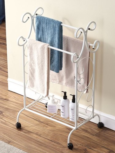 Shabby Chic Bathroom Storage with White standing towel rack with towels.