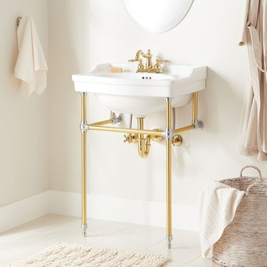 French country bathroom sink with console sink with brass faucet, brass fittings, towels.