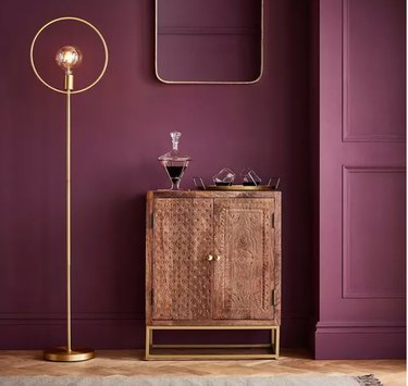 Graham & Brown epoch color of the year with bar cabinet and gold lamp