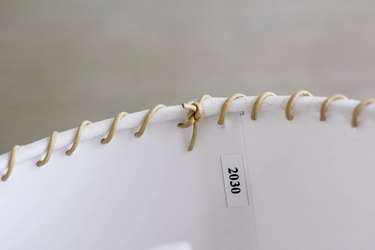 Ends of leather cord tied into knot inside lampshade