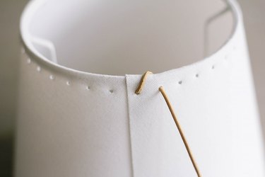 Pulling leather cord up over rim of lampshade