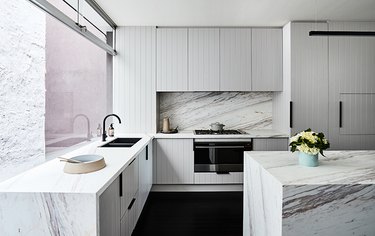 grey beadboard cabinet in kitchen with marble backsplash and island