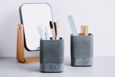 Gray textured concrete toothbrush holders alongside mirror