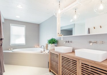 Modern double vanity with white trough sinks, large mirror, corner bathtub and Wall-Mounted Bathroom Faucet