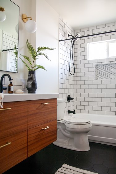 small midcentury modern bathroom with black and white vase and shower with white subway tile