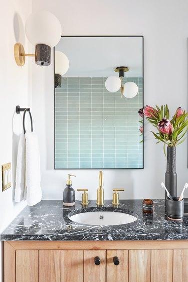 small midcentury modern bathroom with blue tile wall and globe-style light fixtures