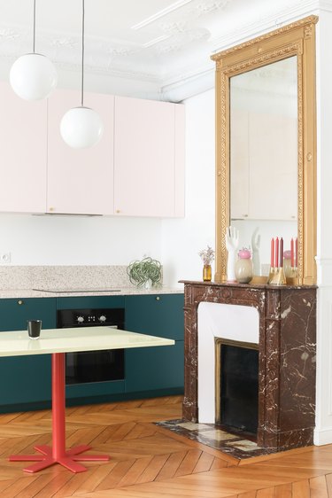 white kitchen with pink and green cabinets with marble fireplace
