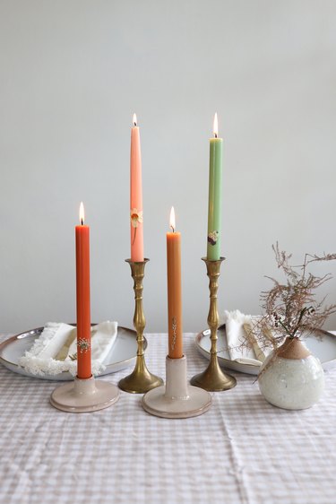 Four colorful pressed flower taper candles grouped together in table centerpiece