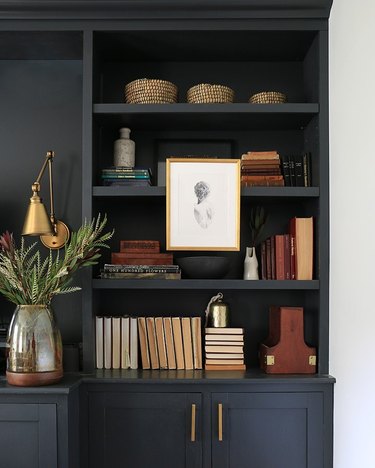 matte black bookcase with books, baskets, art, and vases