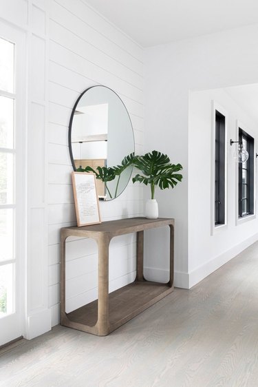 Modern Hallway with console table, mirror, plant, wood floors.
