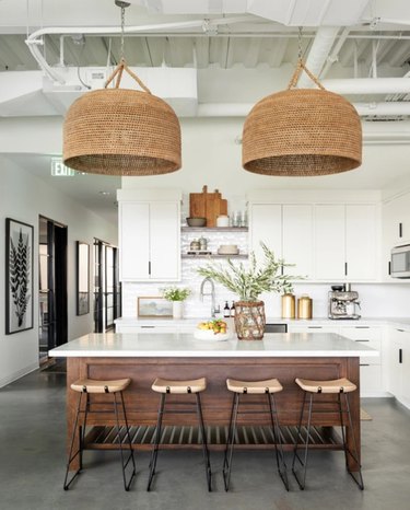large woven rattan lights above white and wood island
