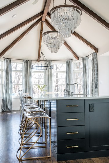crystal chandeliers hanging above traditional black kitchen island