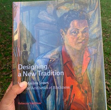 person holding book with title Designing a New Tradition